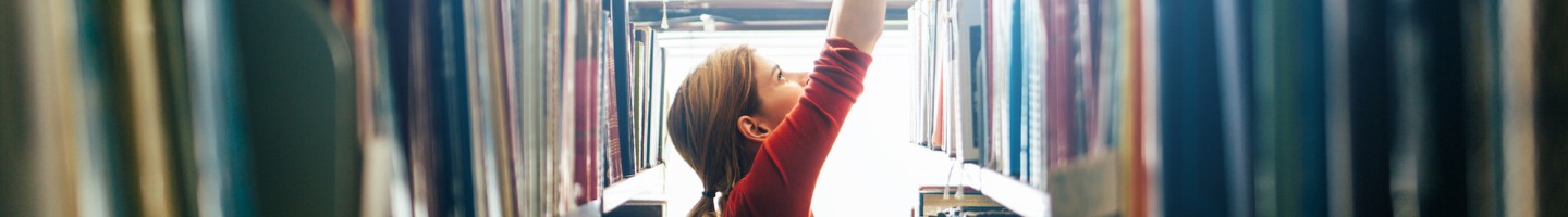 Student reaching for a book in a library