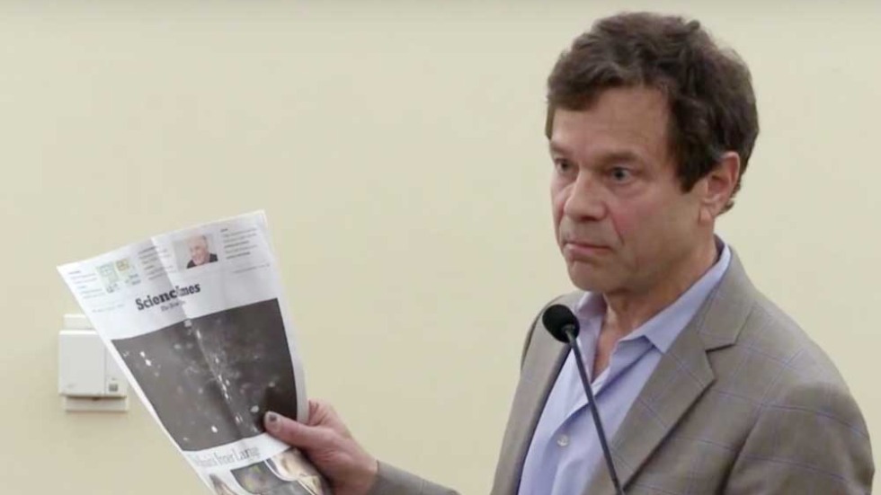 Alan Lightman holding a newspaper